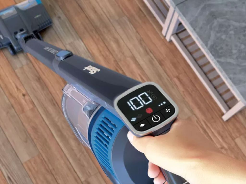hand pushing blue cordless vacuum cleaner