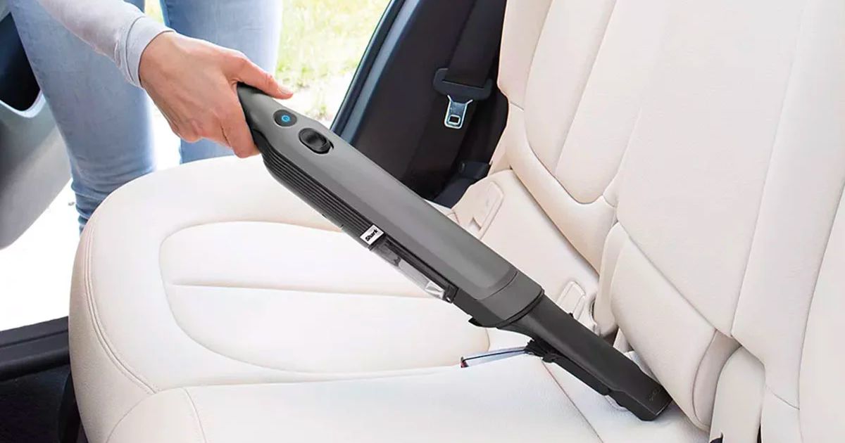  a woman vacuuming a car seat with a Shark cordless stick vac