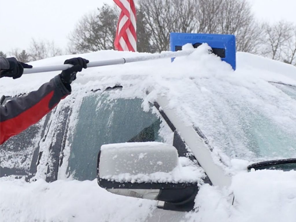 Person cleaning snow off the top of a truck using a Snow Joe Snow Broom