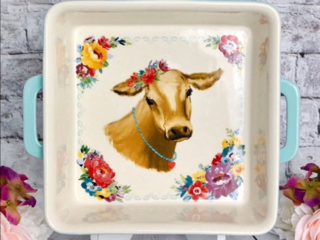 The Pioneer Woman cow graphic baking dish on a stand with gray brick wall in background