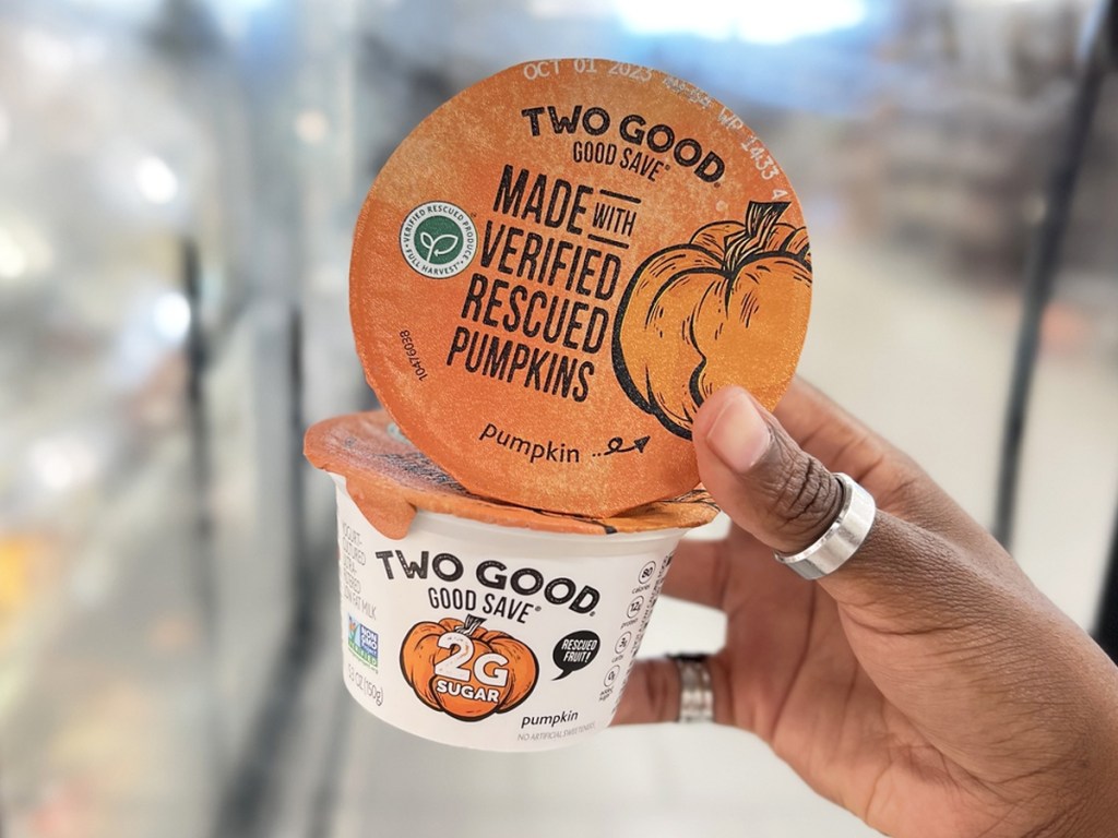 hand holding up containers of Two Good Pumpkin Greek Yogurt