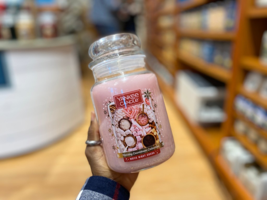 person holding Yankee Candle Movie Night Cocoa Candle in store