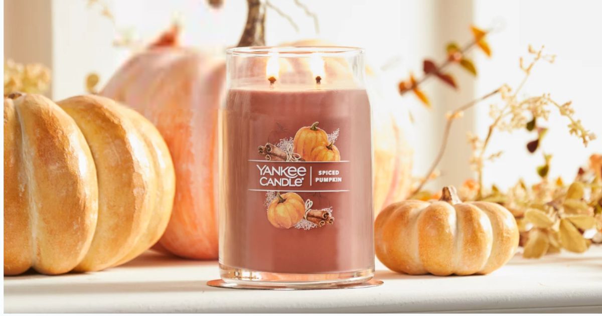 Spiced Pumpkin 2 wick Yankee candle in front of a window in a fall setting with pumpkins and fall foliage