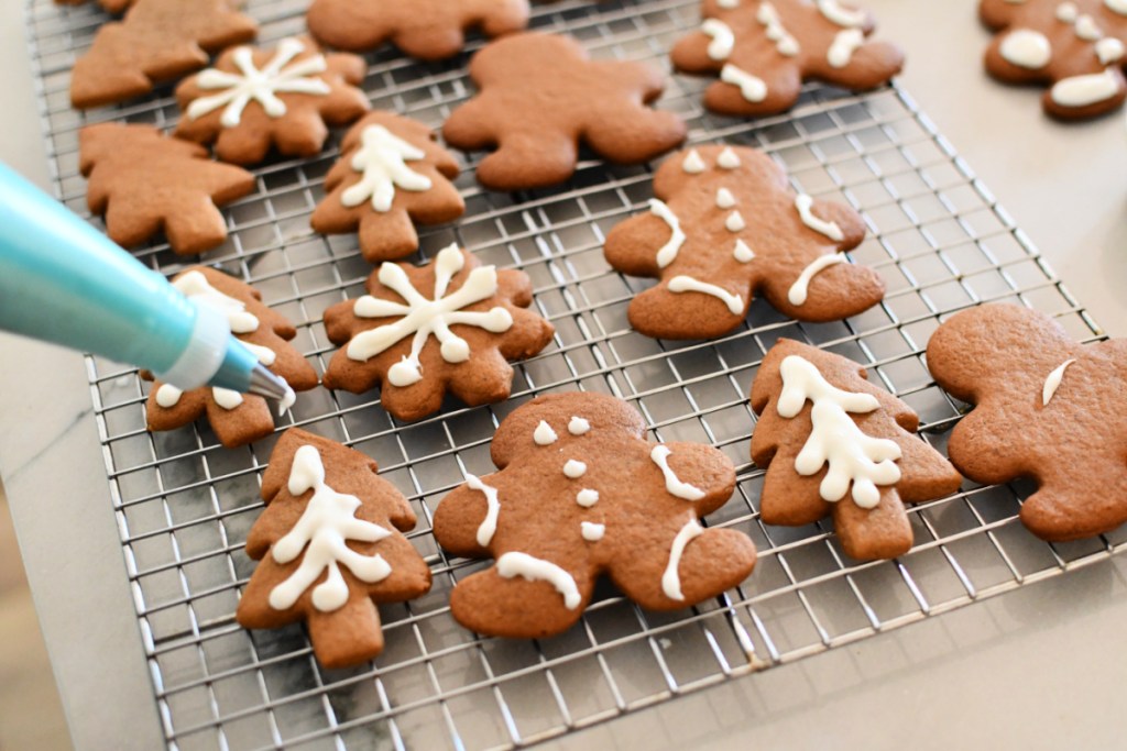 adding frosting to gingerbread cookies