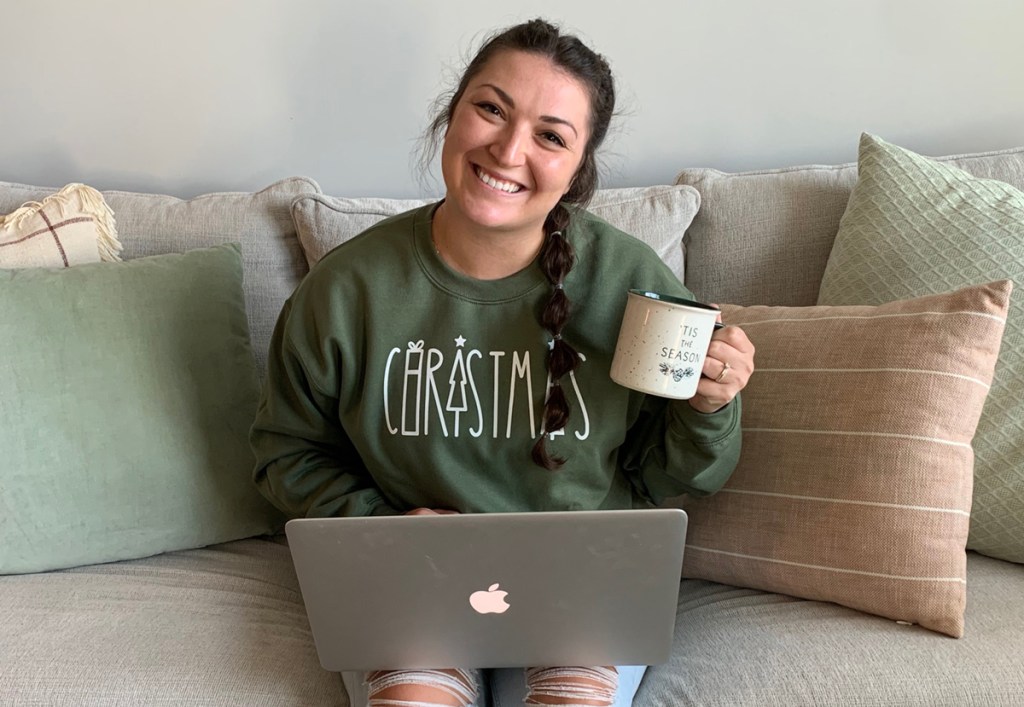 woman in christmas sweatshirt with computer and coffee cup