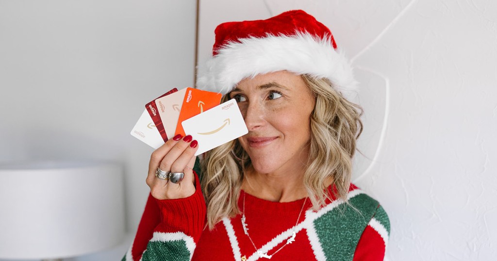 woman in Santa hat holding Amazon gift cards
