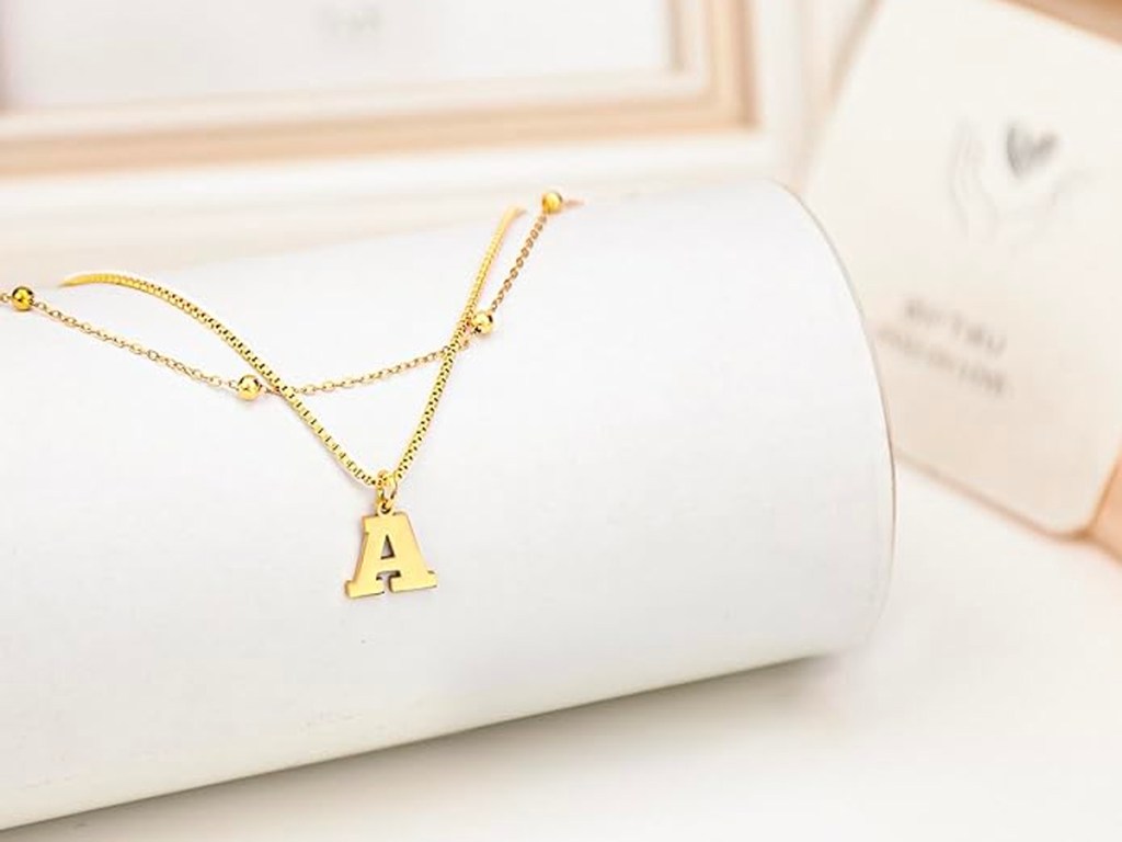 gold initial necklace hanging on display on table