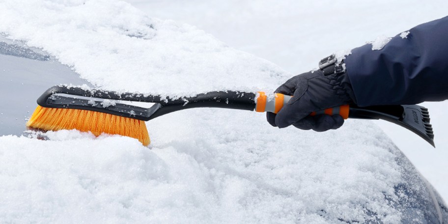 hand using yellow and black ice brush on car 