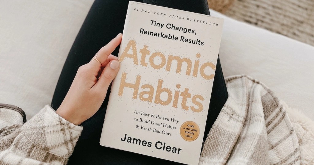 Holding Atomic Habits book on lap