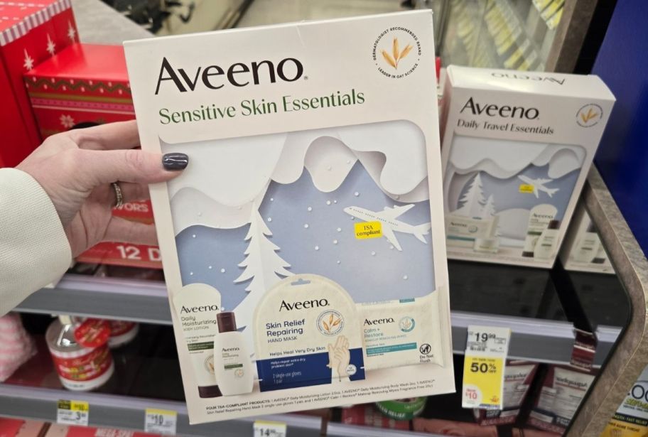 a womans hand holding an aveeno gift set 