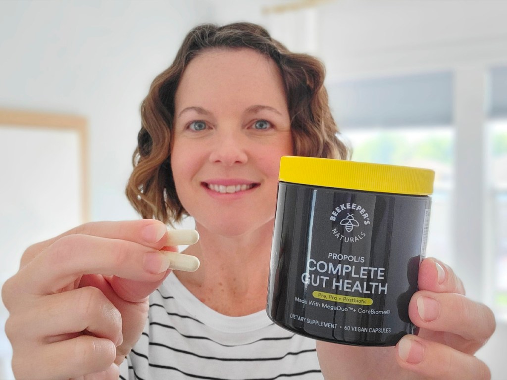 woman holding jar of beekeepers gut health and two pills