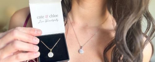 Woman wearing cate & chloe blake necklace while holding a box with the same necklace