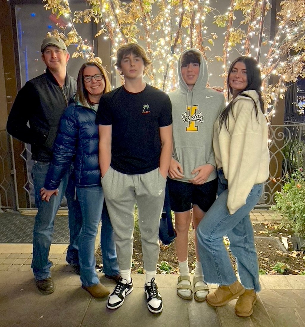 family outside standing in front of lit tree