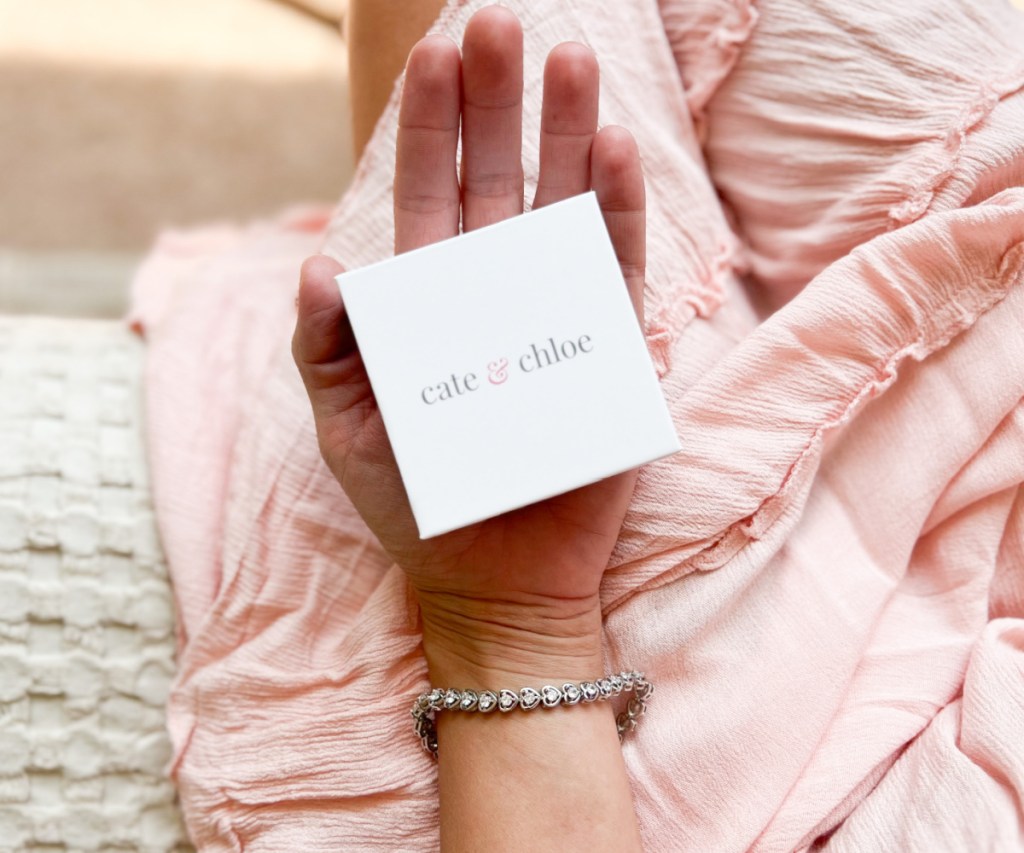 hand with tennis bracelet holding box