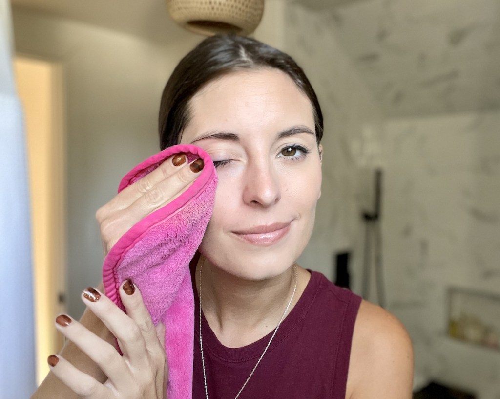 woman wiping off makeup with pink makeup eraser cloth