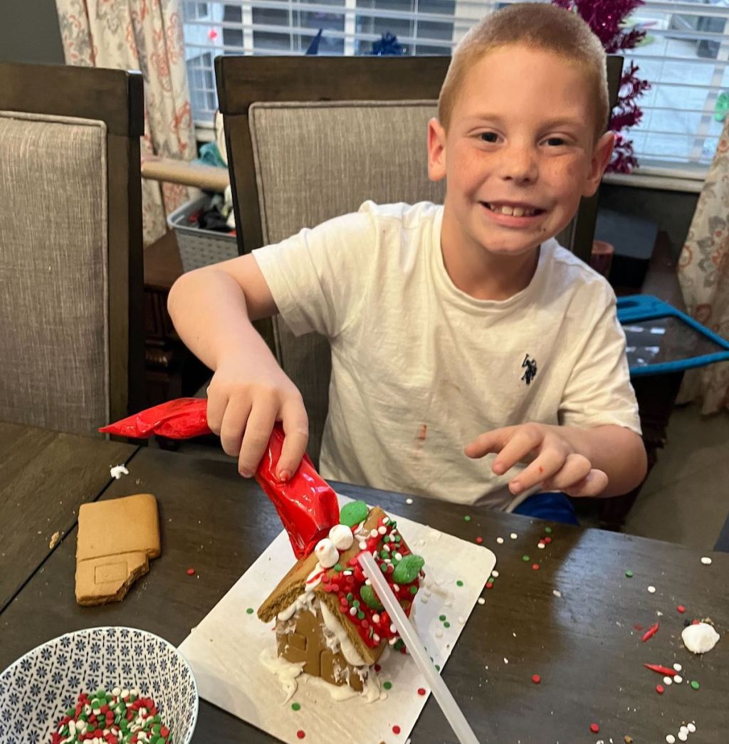 boy sitting at table building gingerbread house
