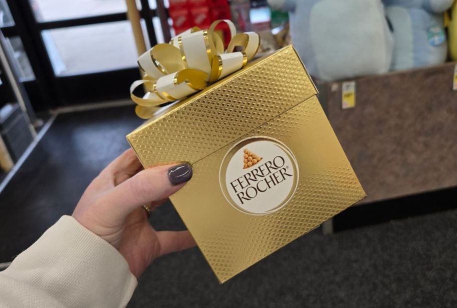 a womans hand holding a gift box of chocolate