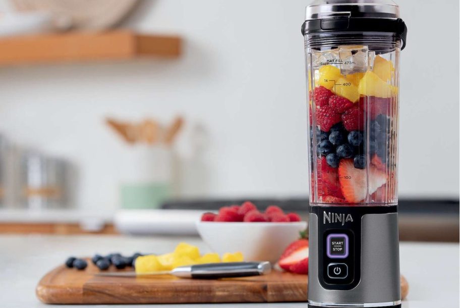 food on cutting block with ninja portable blender with fruit inside