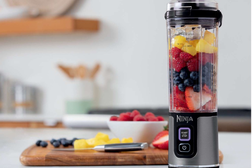 food on cutting board with ninja portable blender with fruit inside
