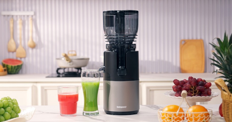 godspeeds cold press juicer and two glasses of juice on a counter