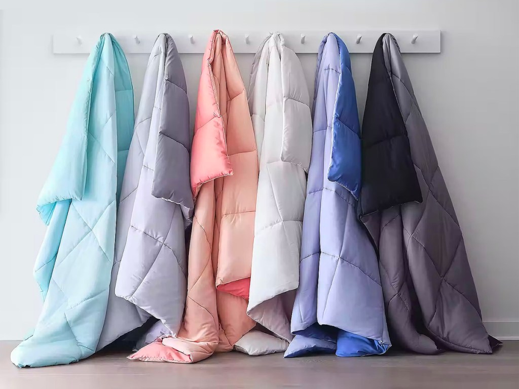 multiple colored comforters hanging from rack