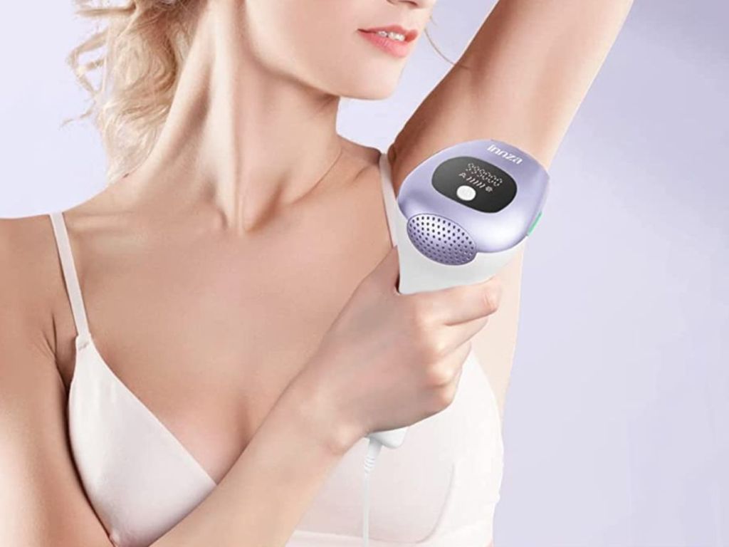 woman using purple hair removal device on under arm