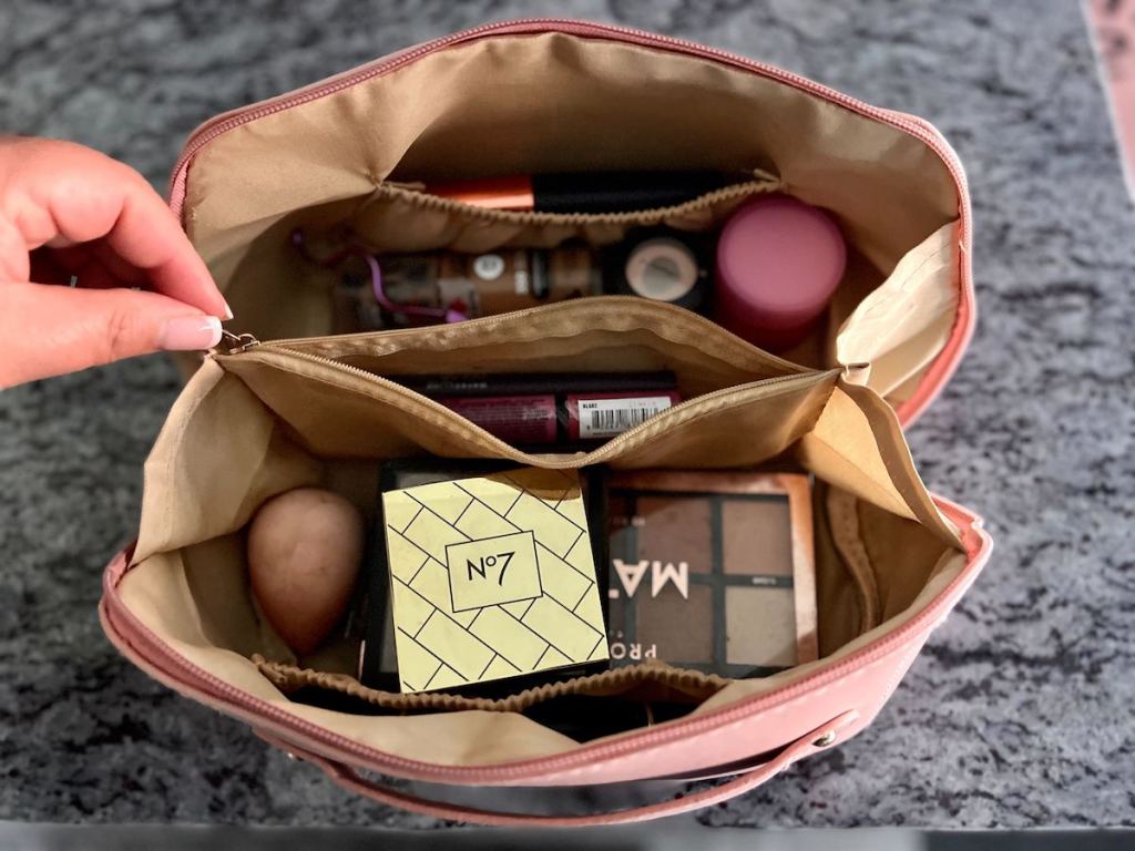 hand holding side of cosmetic bag on counter 