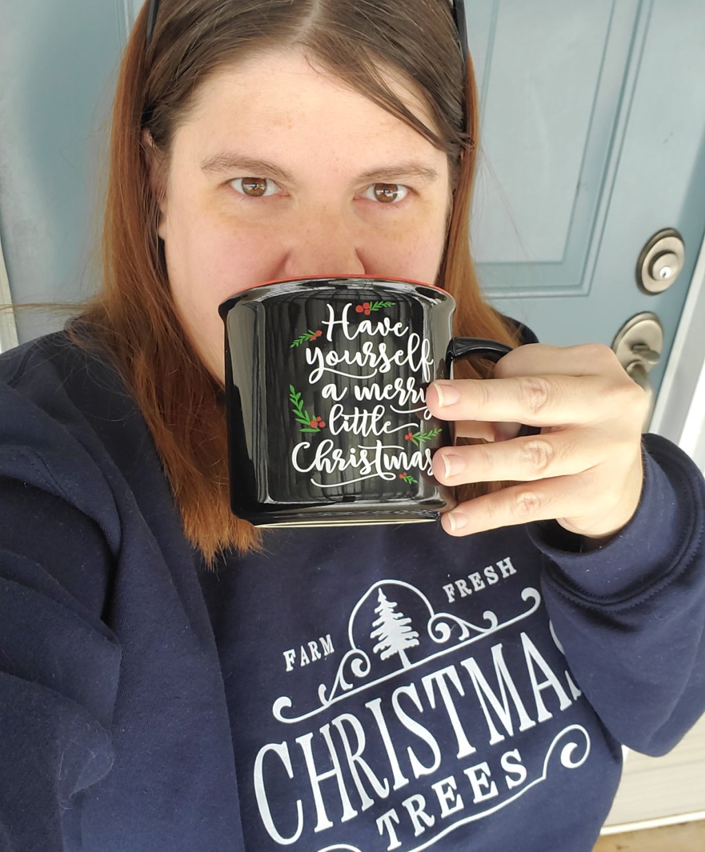 woman in christmas sweatshirt drinking from christmas coffee cup