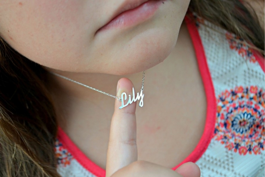 a little girl showing her name necklace
