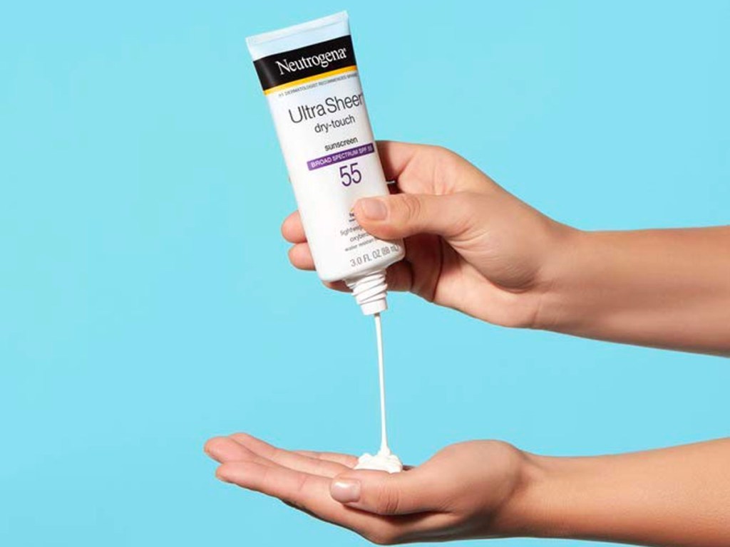 hand squeezing neutrogena ultra sheer sunscreen onto other hand