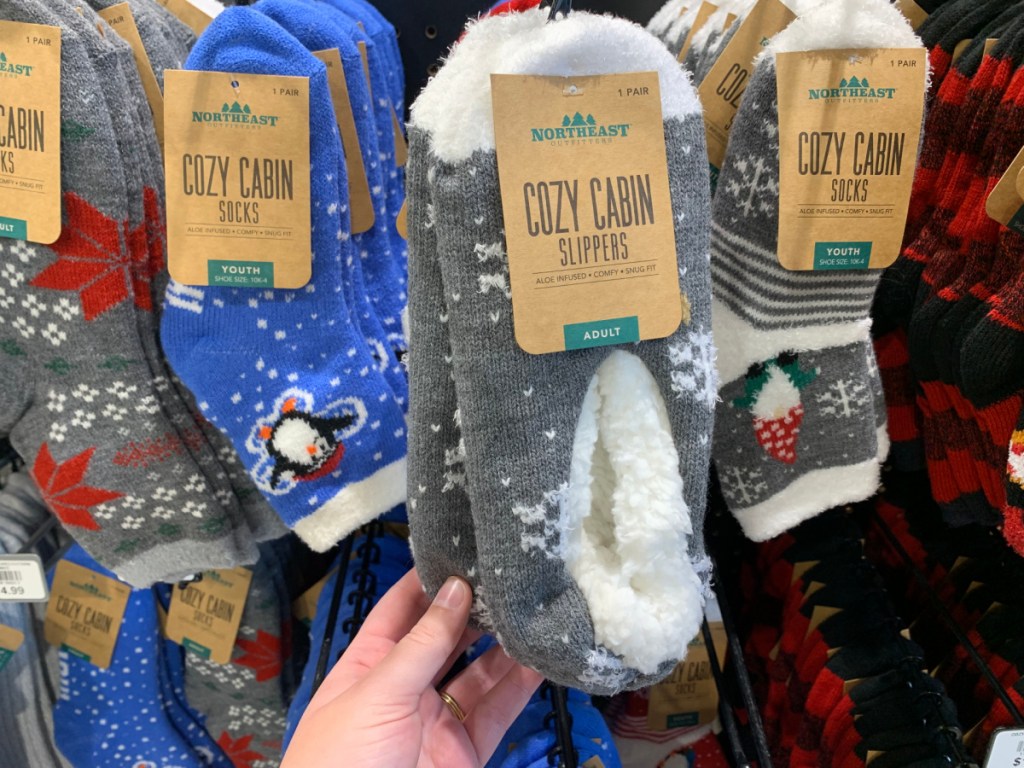 hand lifting a pair of northeast outfitters socks and slippers off a store display