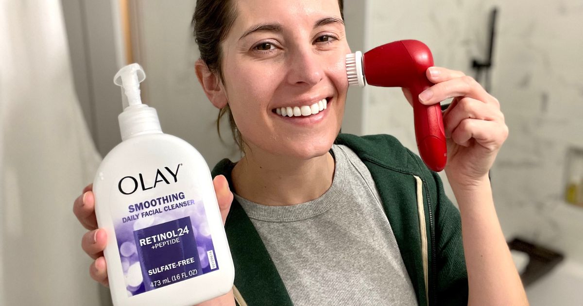 woman holding up Olay cleaner and a facial brush