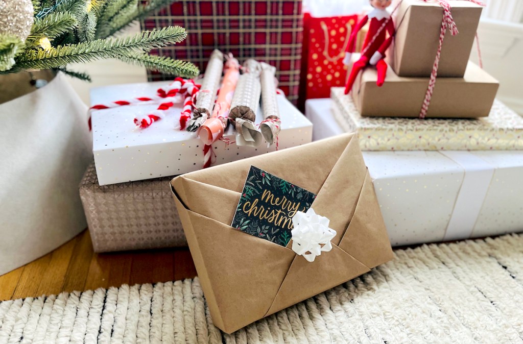christmas packages under christmas tree with merry christmas card and white bow