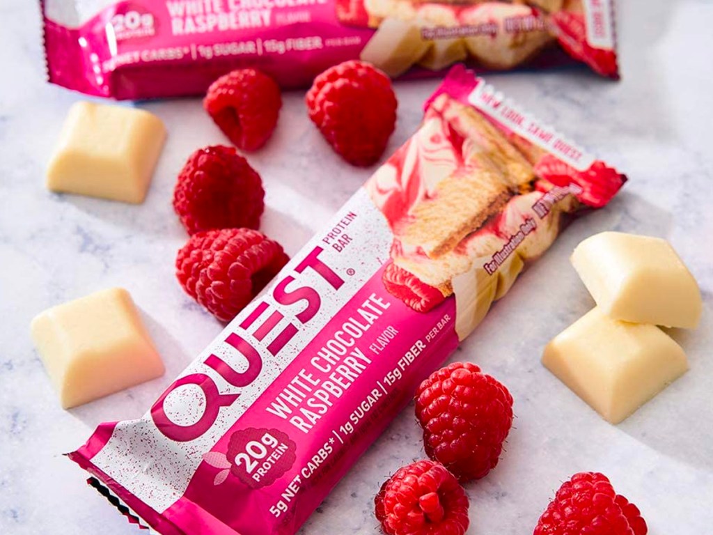 quest chocolate raspberry bar with raspberries and chocoaltes laying next to it