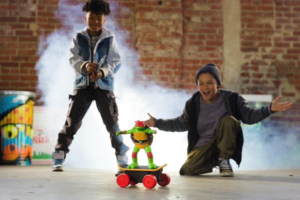 two kids playing with a remote control ninja turtle