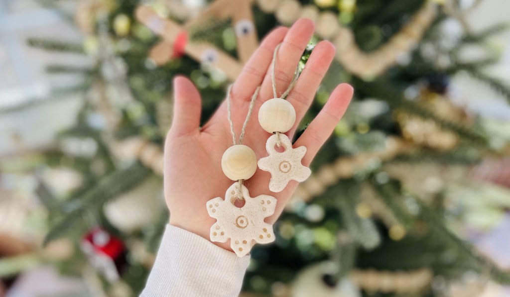 hand holding two salt dough ornaments in front of christmas tree 