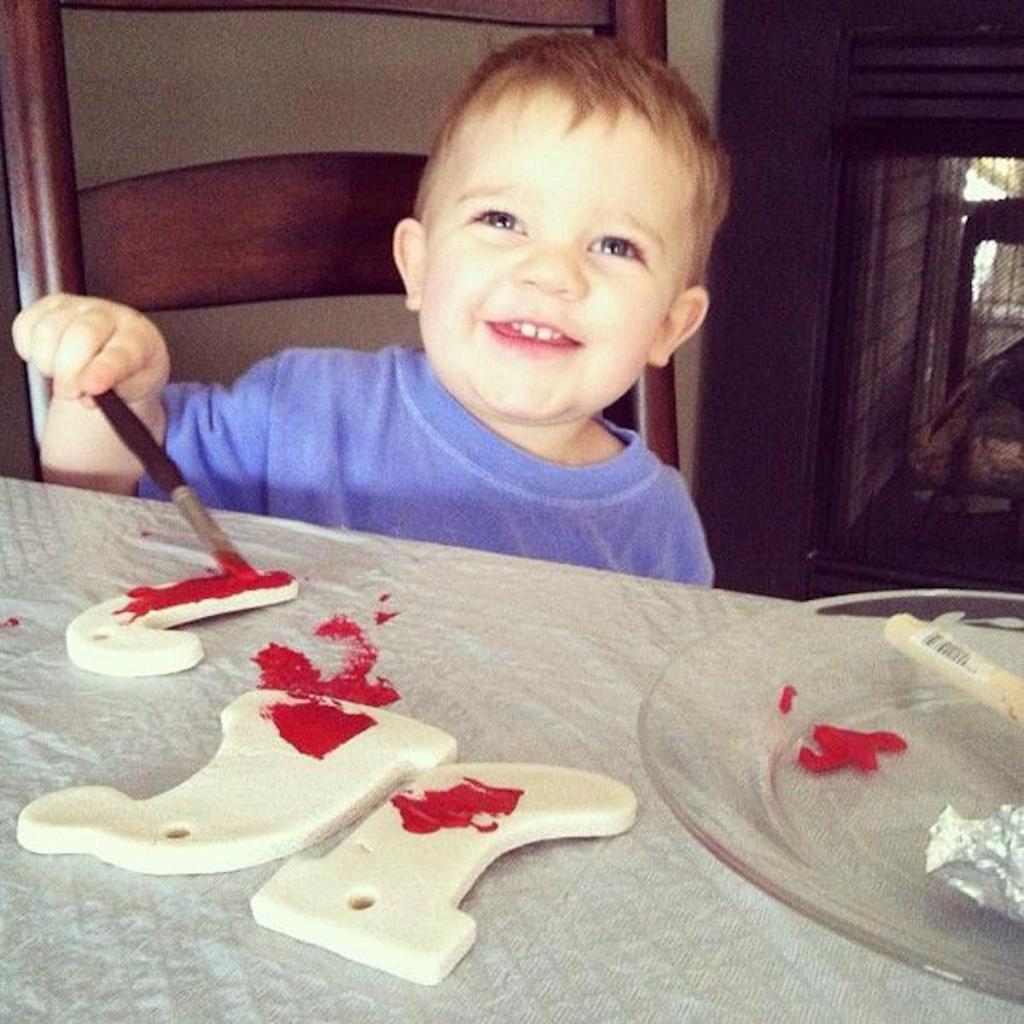 toddler boy sitting at table painting salt dough ornaments
