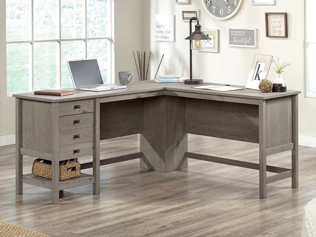 gray sauder L shaped desk with cojmputer and desk lamp