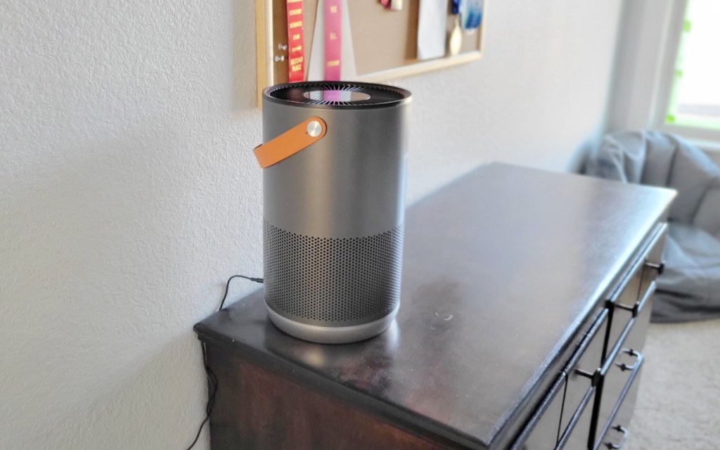 dark grey air purifier with brown handle on dresser