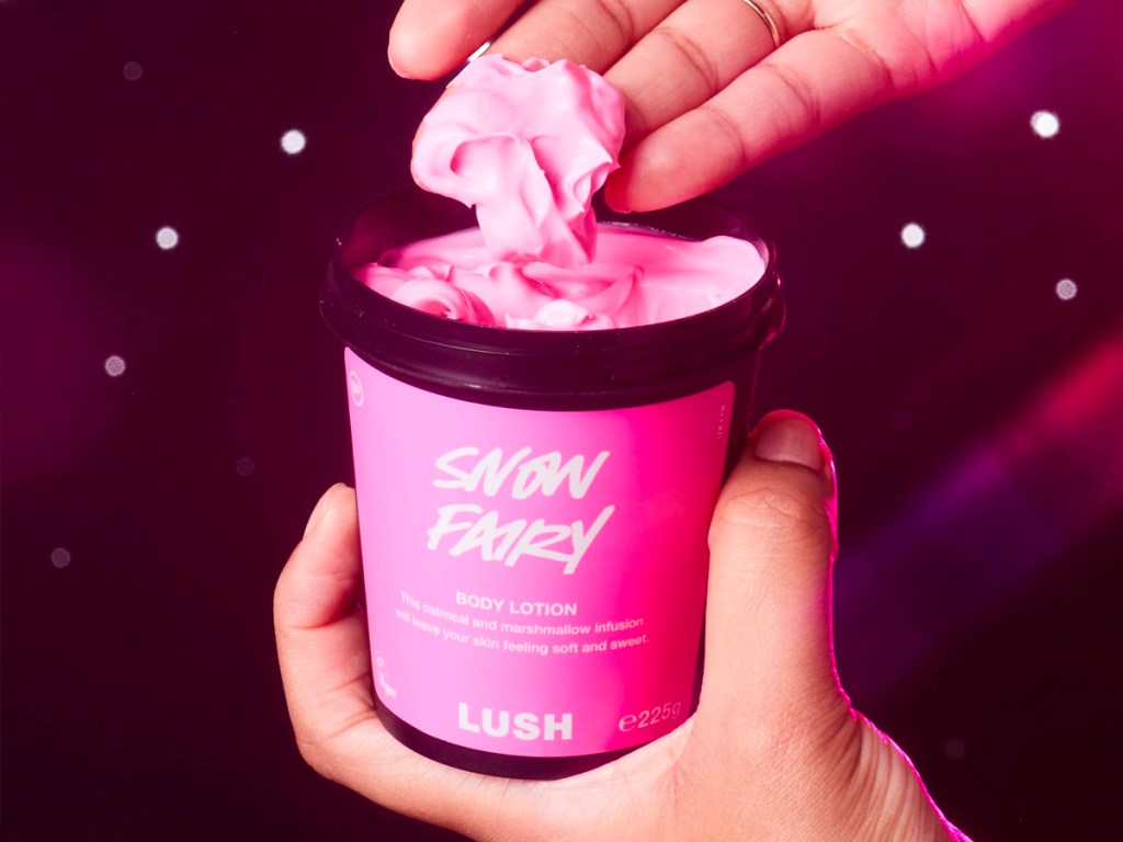 hand scooping pink lotion out of container