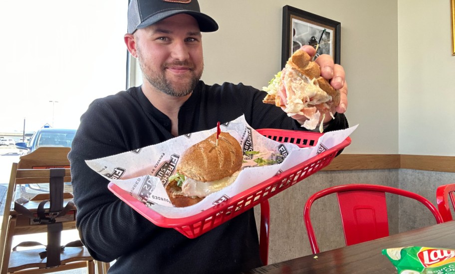 man holding a red basket with a firehouse sub in it