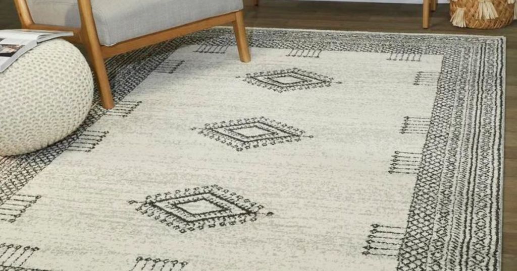white and black rug with diamond shapes on hardwood floor with chair and poof on it