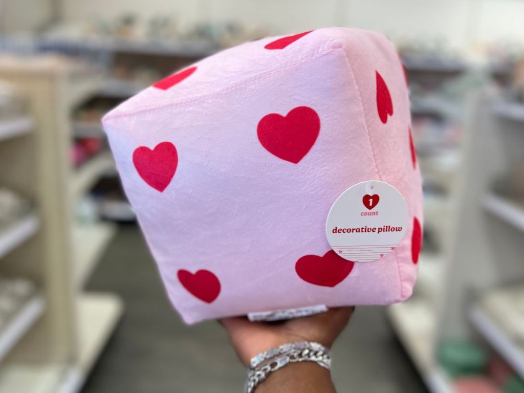 hand holding pink cube pillow with red hearts