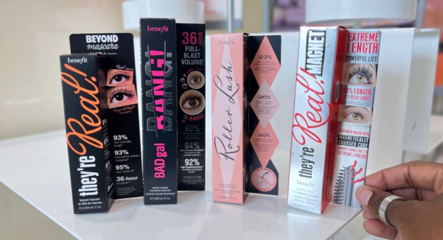 4 benefit mascaras displayed with woman's hand