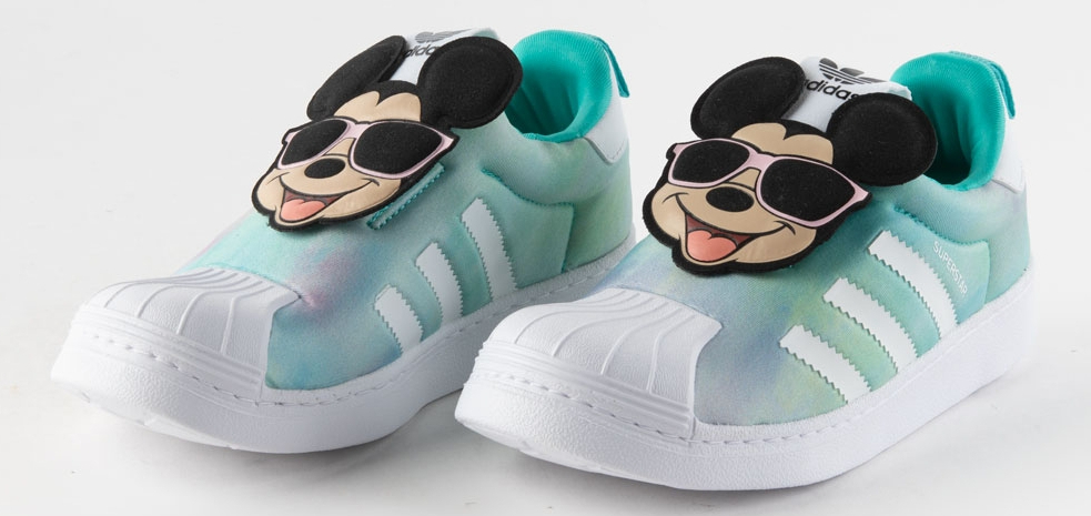 A pair of Adidas kids shoes with Mickey Mouse faces on the laces.