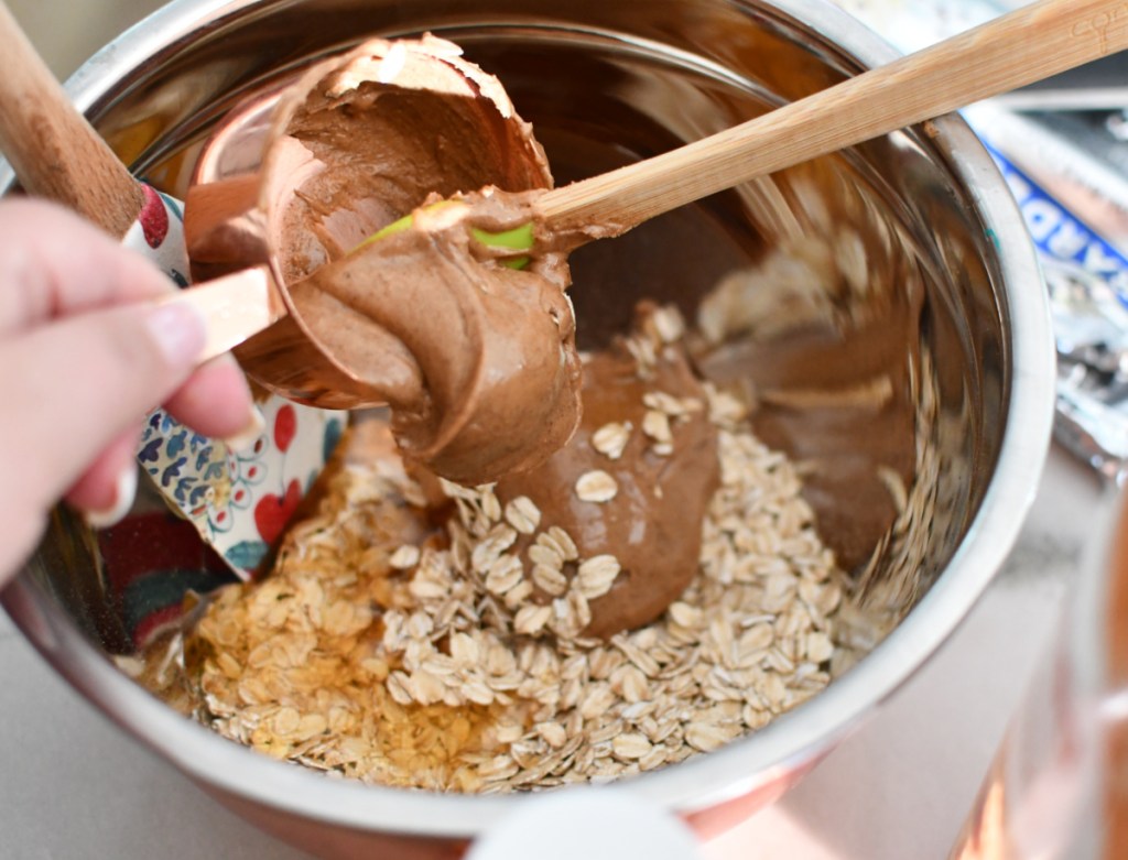 Adding peanut butter to a mixing bowl in order to make oatmeal energy bites 