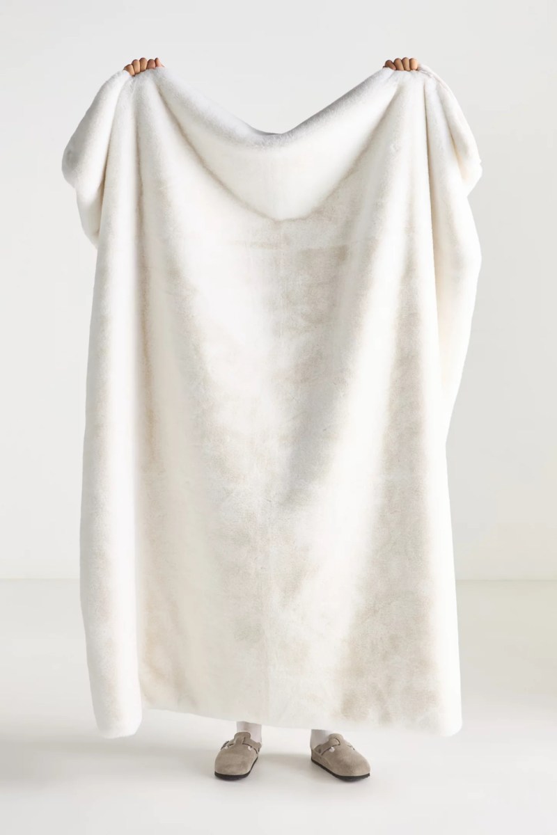 person holding up white faux fur blanket