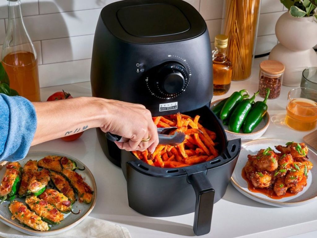hand grabbing food out of a Bella Air Fryer