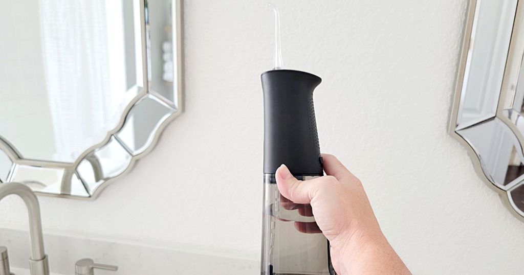 person holding black water flosser in hand