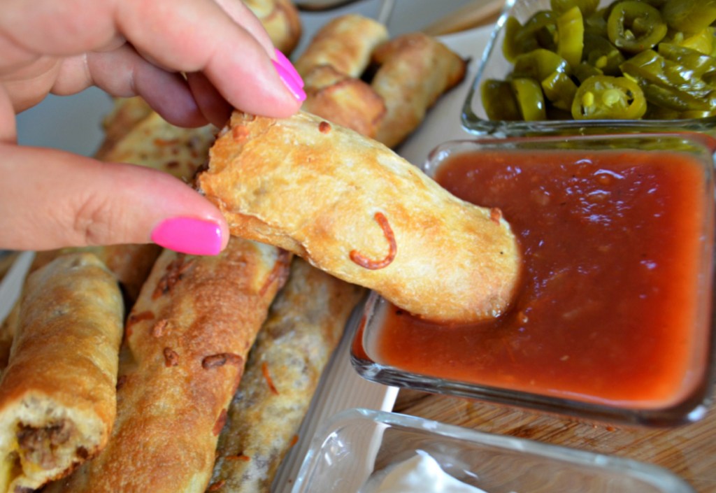 dipping a cheesy taco breadstick gameday appetizer in sauce